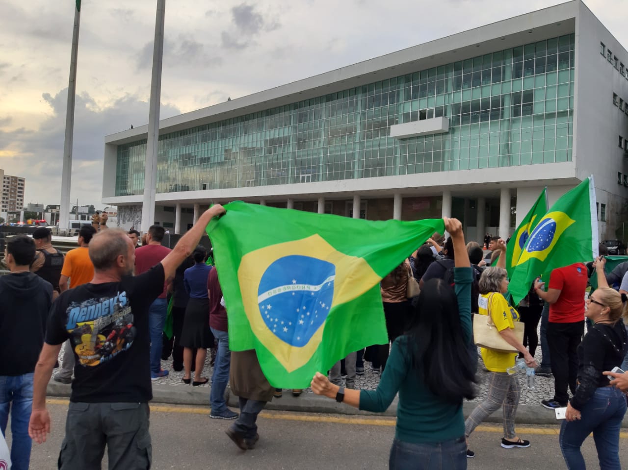Manifestantes pró-Bolsonaro seguram bandeira do Brasil. 