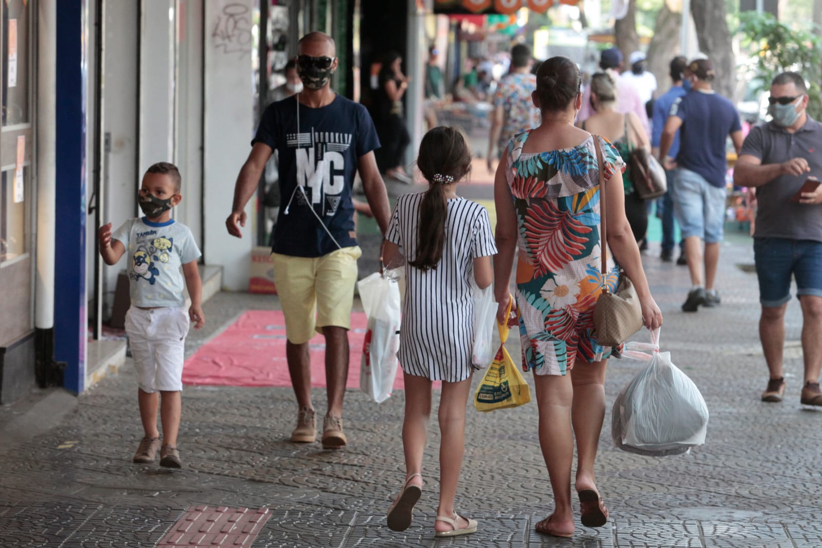  Pessoas caminhando na calçada em uma rua movimentada de comércio em Maringá 