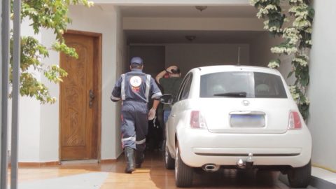  Socorrista do SAMU entra na garagem onde está o veículo, um Fiat 500 branco, enquanto homem coloca a mão na cabeça 