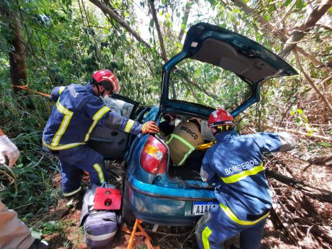  Carro Fiat Palio verde após acidente em ribanceira com esquipes de bombeiros resgatando o motorista 