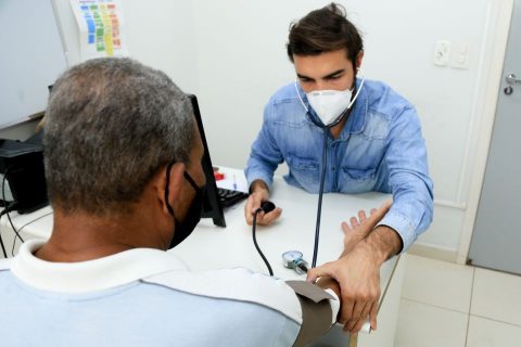  Profissional da saúde mede pressão de paciente homem 