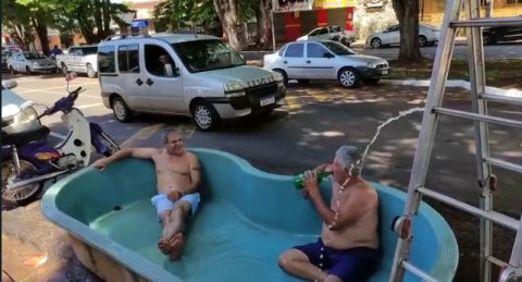  Dois homens brancos sentados em piscina de fibra em vaga de estacionamento 