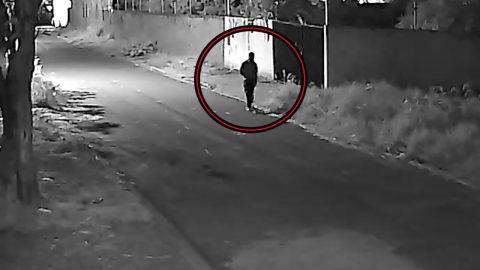  imagem em preto e branco de suspeito de costas no fundo de uma residência na rua durante a noite 