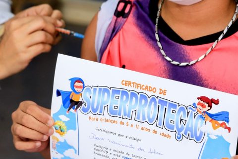  Criança segura certificado de 'superproteção' enquanto toma vacina 