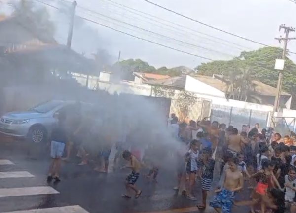 crianças tomando banho de mangueira