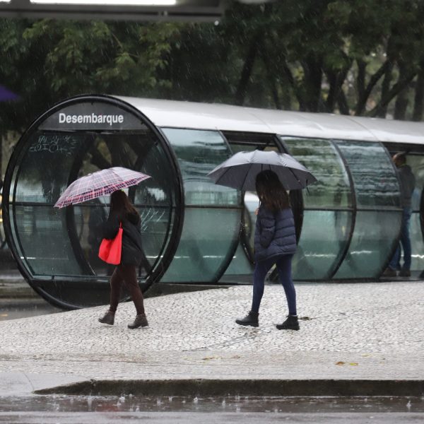 chuva e pessoas caminhando próximo a estação-tubo