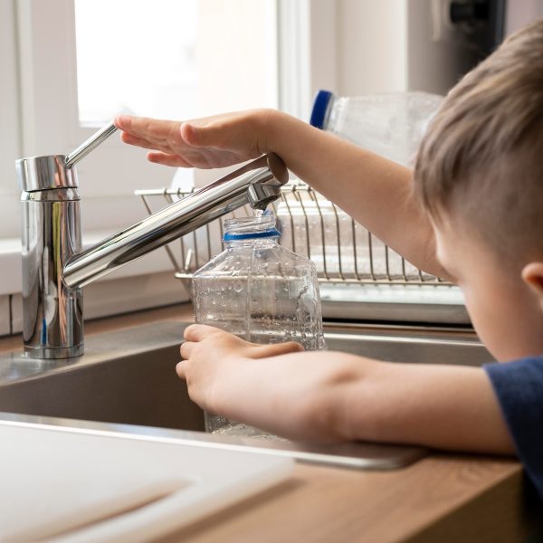  criança enchendo garrafa de água na torneira 