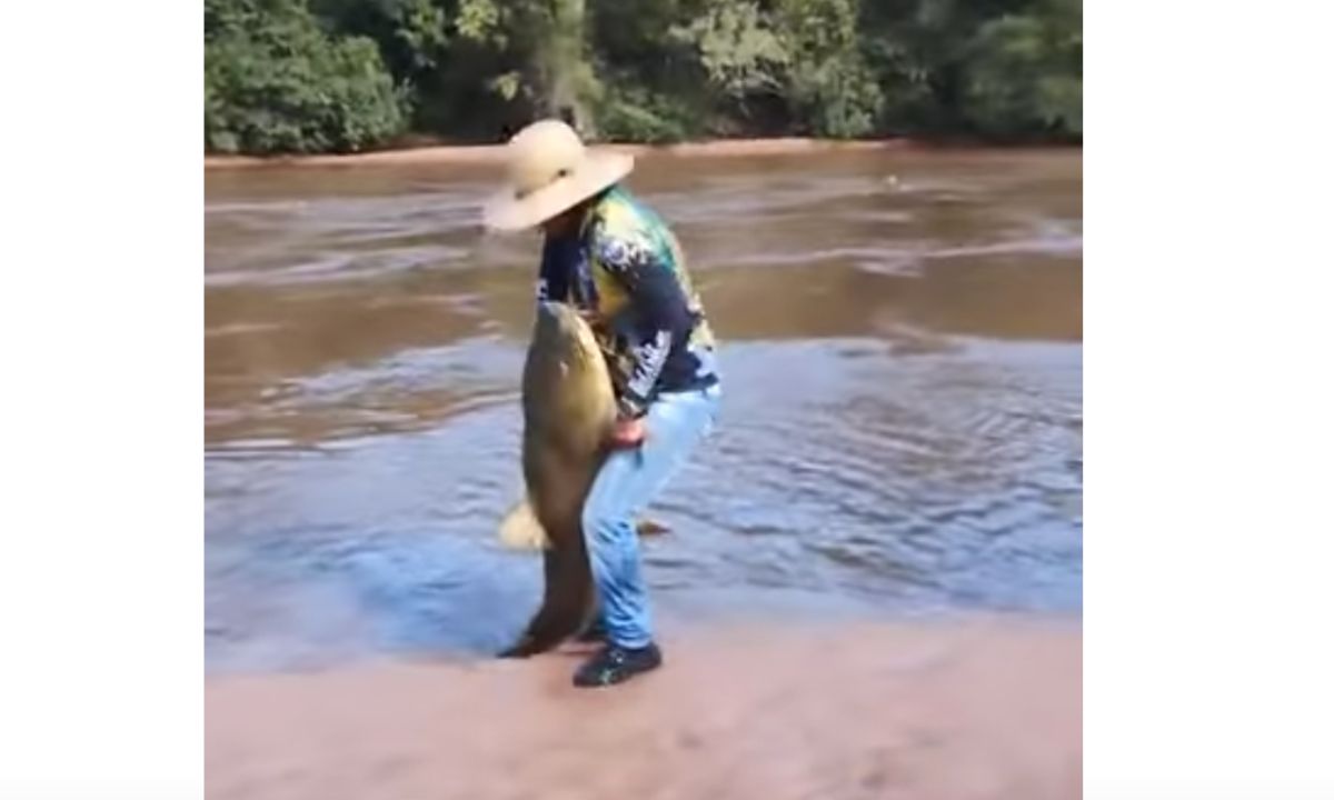 Cafu levanta o peixe, após tirá-lo da água