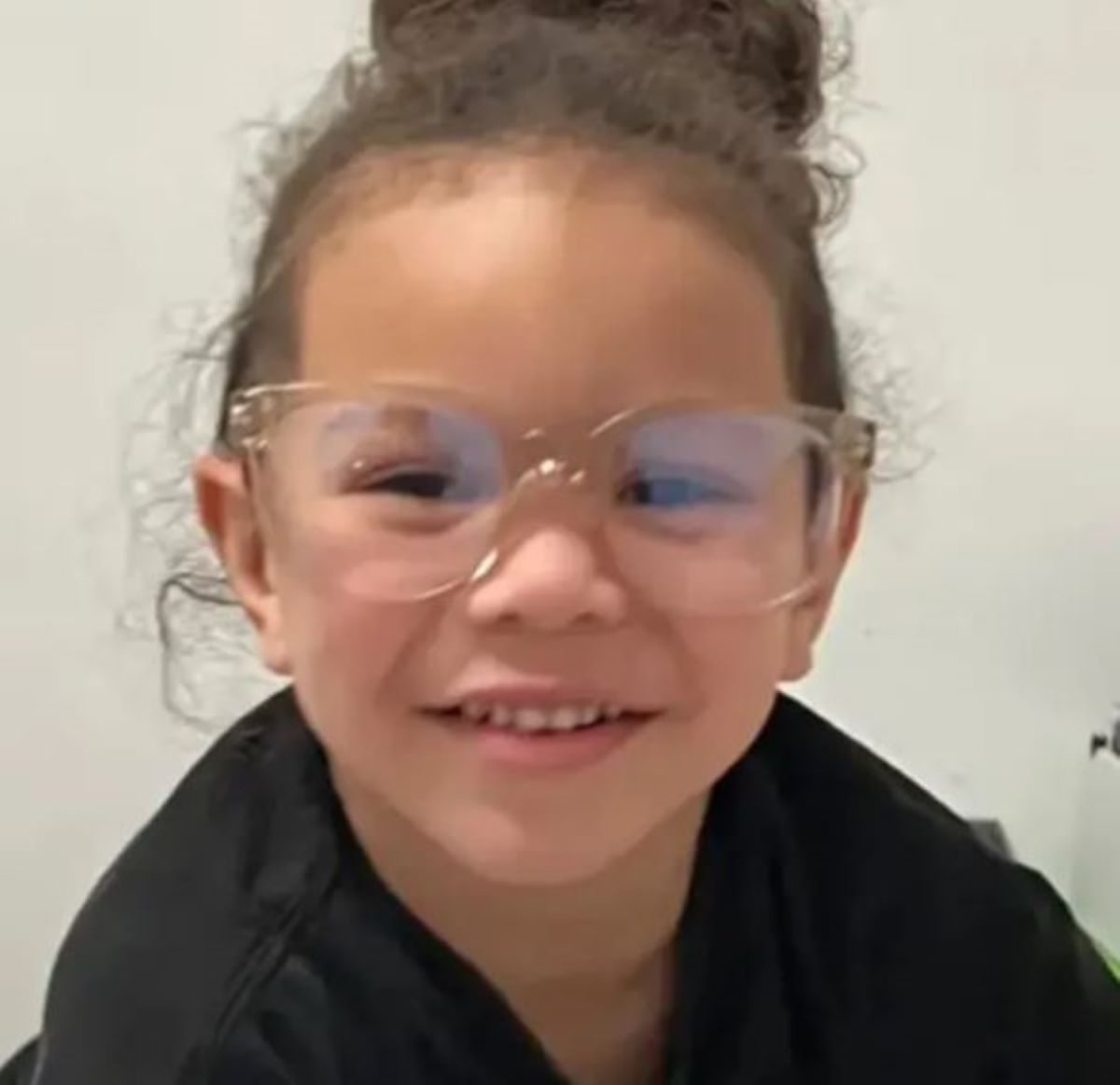  criança usando óculos de grau sorrindo para foto 