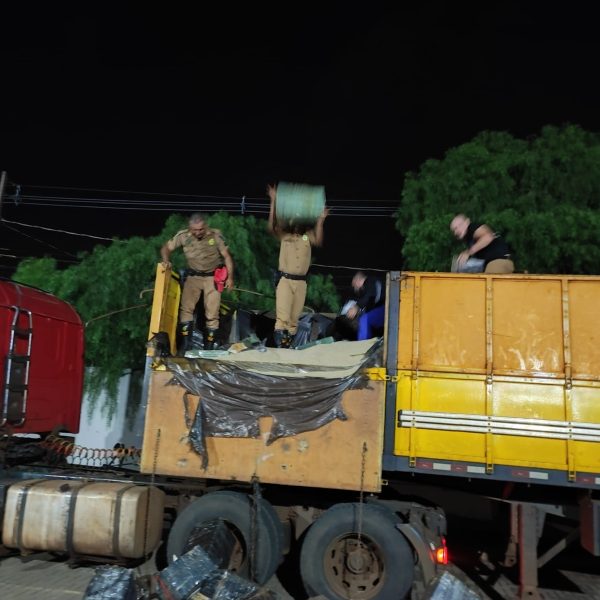 Policiais descarregando o caminhão após identificar os pacotes de maconha embaixo do arroz.
