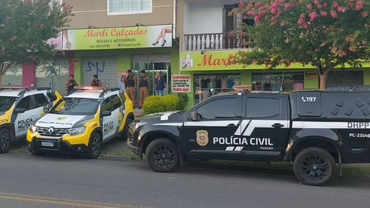 A Polícia Civil do Paraná (PCPR) concluiu o inquérito sobre o homicídio de Bruno da Silva Cardoso, de 33, ocorrido no dia 10 de janeiro deste ano, no bairro Cajuru, em Curitiba. A vítima foi morta dentro da loja de calçados da família, na frente de seu filho. Ao longo das investigações a polícia identificou os dois atiradores, que acertaram oito tiros na vítima. No entanto, somente um deles está preso. Assim, a polícia pede ajuda para localizar o outro suspeito, que está foragido.